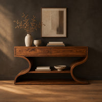 Console table with s shaped side supports and a lower shelf in a dark studio against a charcoal plaster wall