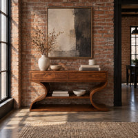 Console table with s shaped side supports and a lower shelf in an industrial loft entryway with exposed brick