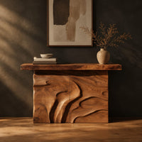 Console table on a solid base carved with flowing relief in a dark studio against a charcoal plaster wall