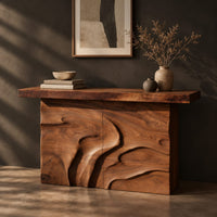 Console table on a solid base carved with flowing relief, three-quarter view showing the grain