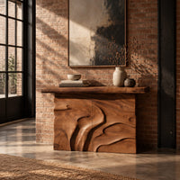 Console table on a solid base carved with flowing relief in an industrial loft entryway with exposed brick
