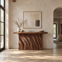 Console table with a thick slab top and a deeply carved two panel body in a bright open plan entryway