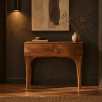 Console table with slim tapered legs and a boxy two panel top in a dark entryway at golden hour