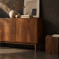 Corner detail of console table with three drawers and a door on tapered legs beside wood, brass and linen samples
