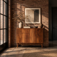 Console table with three drawers and a door on tapered legs in an industrial loft entryway with exposed brick