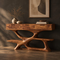 Corner detail of console table with three drawers over a twisting open loop base and low shelf beside wood, brass and linen samples