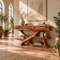 Console table with three drawers over a twisting open loop base and low shelf in a bright entryway with arched windows and plants
