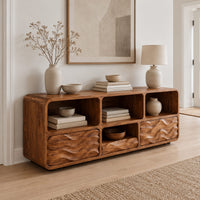 Low console cabinet with three open cubbies above two wave carved front panels in a Scandinavian entryway with white walls