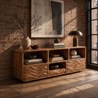 Low console cabinet with three open cubbies above two wave carved front panels in an industrial loft entryway with exposed brick