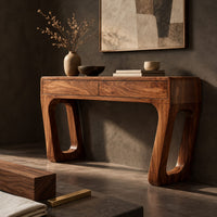 Corner detail of console table with a two panel front and angled legs with oblong slots beside wood, brass and linen samples