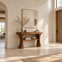 Console table with two waisted sculpted legs and a single open shelf below in a bright open plan entryway