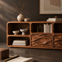 Corner detail of console table with wave carved front panels and open cubbies beside wood, brass and linen samples