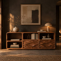 Console table with wave carved front panels and open cubbies in a dark entryway at golden hour
