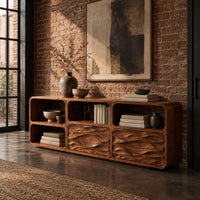 Console table with wave carved front panels and open cubbies in an industrial loft entryway with exposed brick