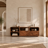 Console table with wave carved front panels and open cubbies in a bright open plan entryway