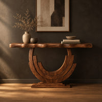 Wood console table with a wavy edge top on a layered arc base in a dark studio against a charcoal plaster wall
