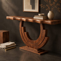 Corner detail of wood console table with a wavy edge top on a layered arc base beside wood, brass and linen samples