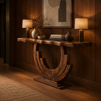 Wood console table with a wavy edge top on a layered arc base in an evening entryway with walnut wall paneling
