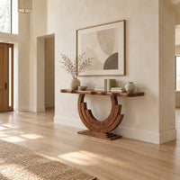 Wood console table with a wavy edge top on a layered arc base in a bright open plan entryway