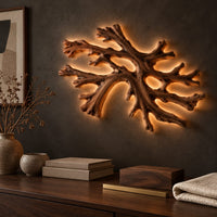 Corner detail of coral shaped branching wall light with a warm halo of glow behind it beside wood, brass and linen samples