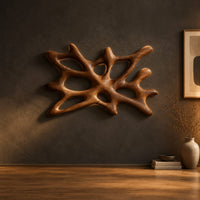 Branching wooden wall sconce with oval openings and a halo of light in a dark studio against a charcoal plaster wall