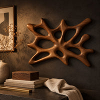 Corner detail of branching wooden wall sconce with oval openings and a halo of light beside wood, brass and linen samples