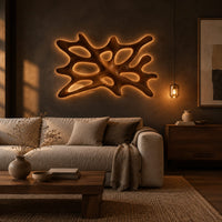 Branching wooden wall sconce with oval openings and a halo of light in a dark living room at golden hour