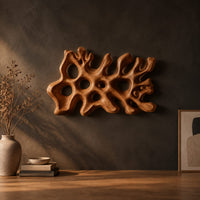Wide wall sconce shaped like branching coral with pierced openings in a dark studio against a charcoal plaster wall