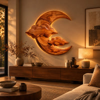 Carved wood crescent moon wall art with two cloud shapes across its face above a low console in an evening living room
