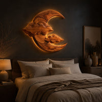 Carved wood crescent moon wall art with two cloud shapes across its face above a bed in a dusk lit bedroom
