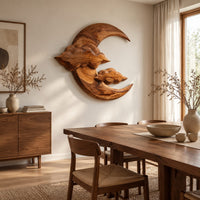 Carved wood crescent moon wall art with two cloud shapes across its face beside a dining table in natural light