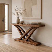 Console table with crossing bowed legs on a thick base and a plank top in a Scandinavian entryway with white walls
