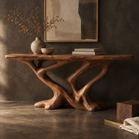 Corner detail of console table with a slab top on crossing limbs and root style feet beside wood, brass and linen samples