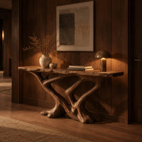 Console table with a slab top on crossing limbs and root style feet in an evening entryway with walnut wall paneling