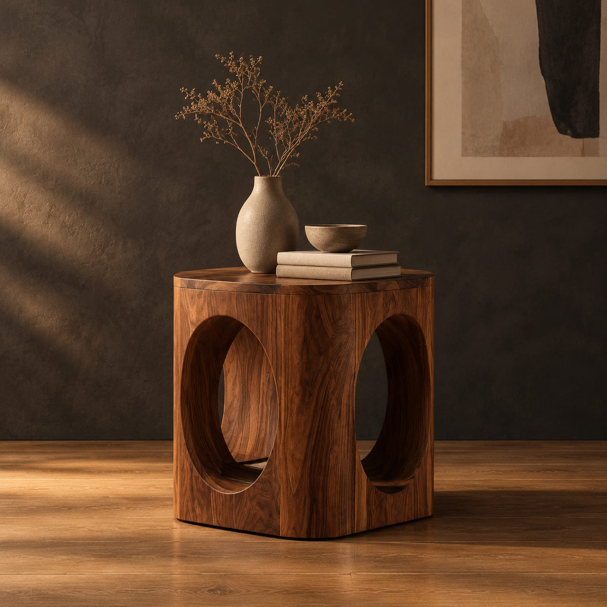 Cube shaped side table with large oval cut outs and softened edges in a dark studio against a charcoal plaster wall