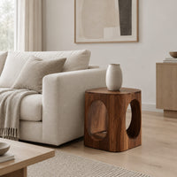 Cube shaped side table with large oval cut outs and softened edges in a Scandinavian living room with white walls