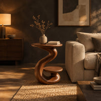 Curling swirl side table with a wide top and a small nested disc shelf in a dark living room at golden hour