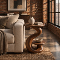 Curling swirl side table with a wide top and a small nested disc shelf in an industrial loft living room with exposed brick