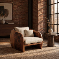 Barrel chair with curved solid wood sides and a deep cream seat cushion in an industrial loft living room with exposed brick