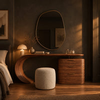 Makeup vanity with a sweeping curved leg and a block of three drawers in a dark bedroom at golden hour