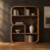 Bookshelf with a thick curved frame and open cubbies of mixed sizes in a dark studio against a charcoal plaster wall