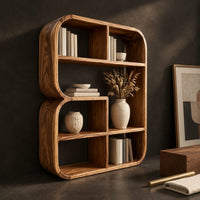 Corner detail of bookshelf with a thick curved frame and open cubbies of mixed sizes beside wood, brass and linen samples