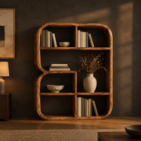 Bookshelf with a thick curved frame and open cubbies of mixed sizes in a dark living room at golden hour