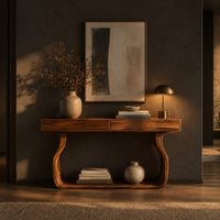 Slim console table on bowed sculpted legs joined by a wide floor rail in a dark entryway at golden hour