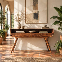 Curved console table with two drawers, open shelf and tapered legs in a bright entryway with arched windows and plants