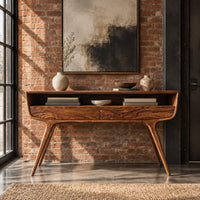 Curved console table with two drawers, open shelf and tapered legs in an industrial loft entryway with exposed brick