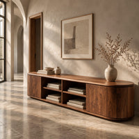 Corner detail of long tv stand with curved ends, solid end panels and four open center cubbies beside wood, brass and linen samples