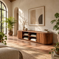 Long tv stand with curved ends, solid end panels and four open center cubbies in a bright living room with arched windows and plants