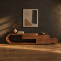 Low tv stand with a looped end and stepped wooden boxes in a dark studio against a charcoal plaster wall