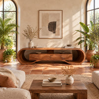 Tv stand with a looping curved frame and a wave carved center box in a bright living room with arched windows and plants